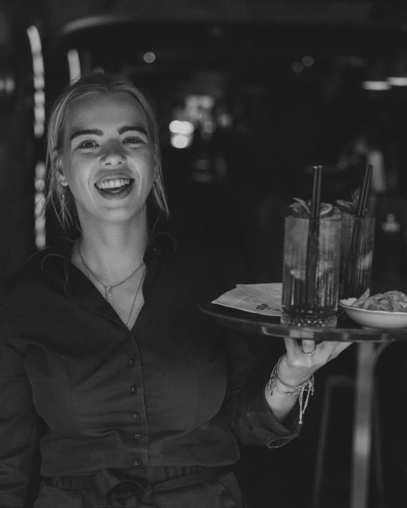 Medewerker van Bar Ella met een dienblad met drankjes